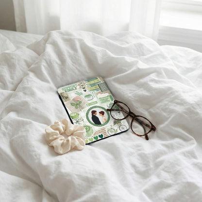 Kindle cover with "Support Kindle" and green book-themed stickers, next to glasses.