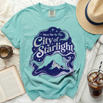 Teal t-shirt with "Meet Me In The City of Starlight" graphic featuring mountains.