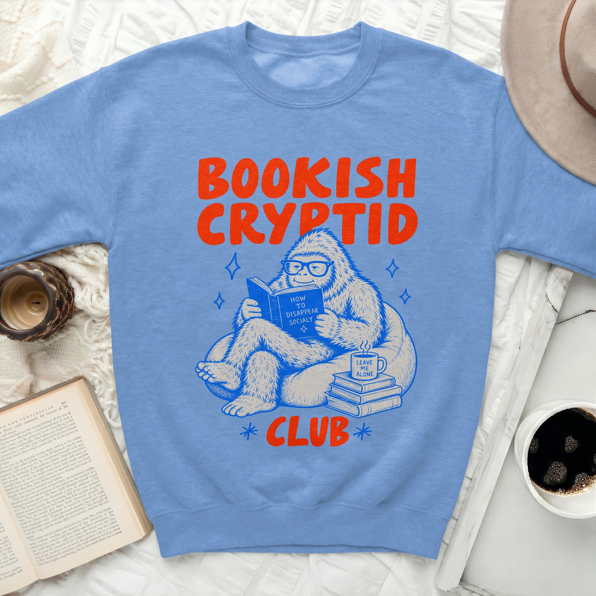 Blue sweatshirt with a Bigfoot reading a book, text "Bookish Cryptid Club".