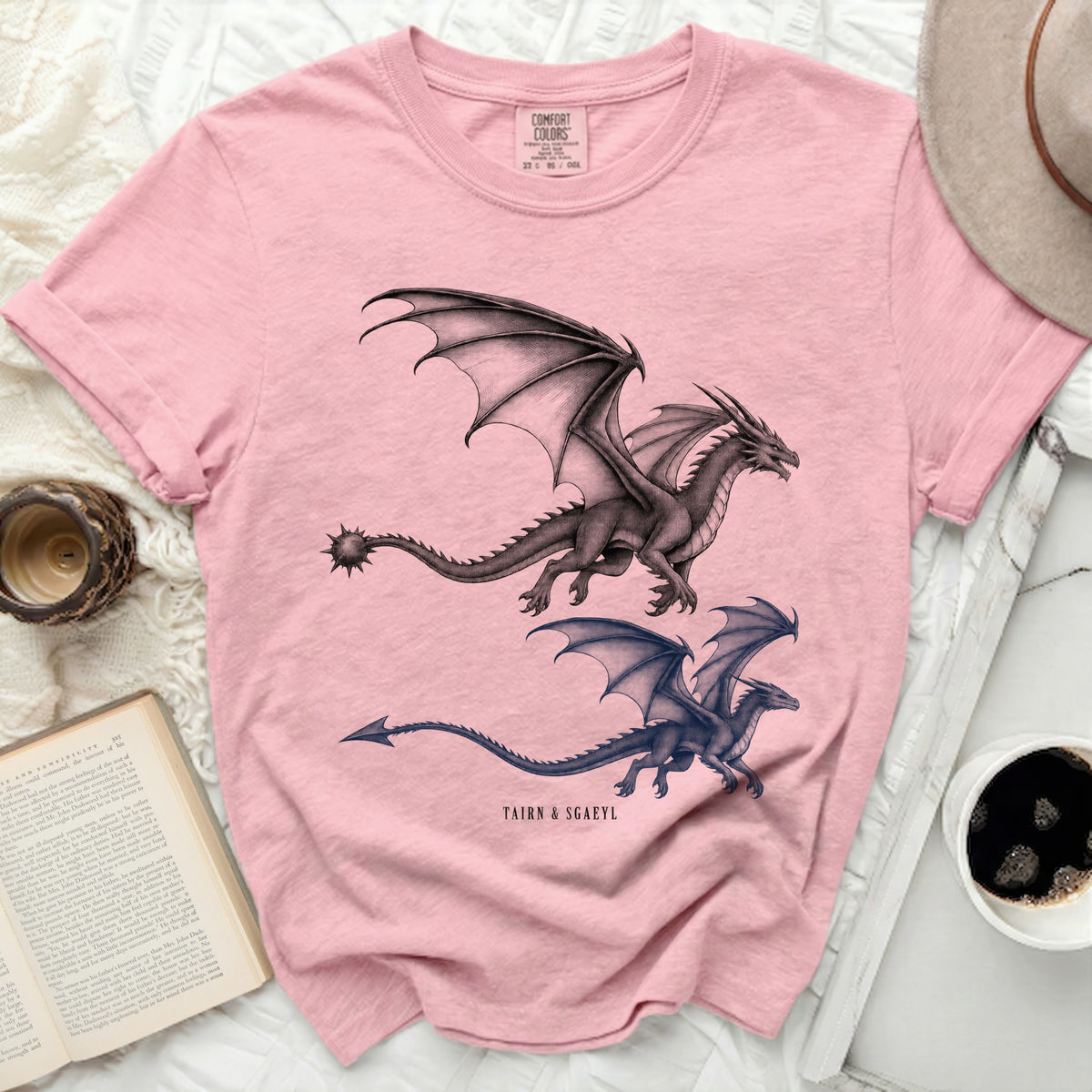 Pink t-shirt with two black and grey dragons and text "TAIRN & SGAEYL".
