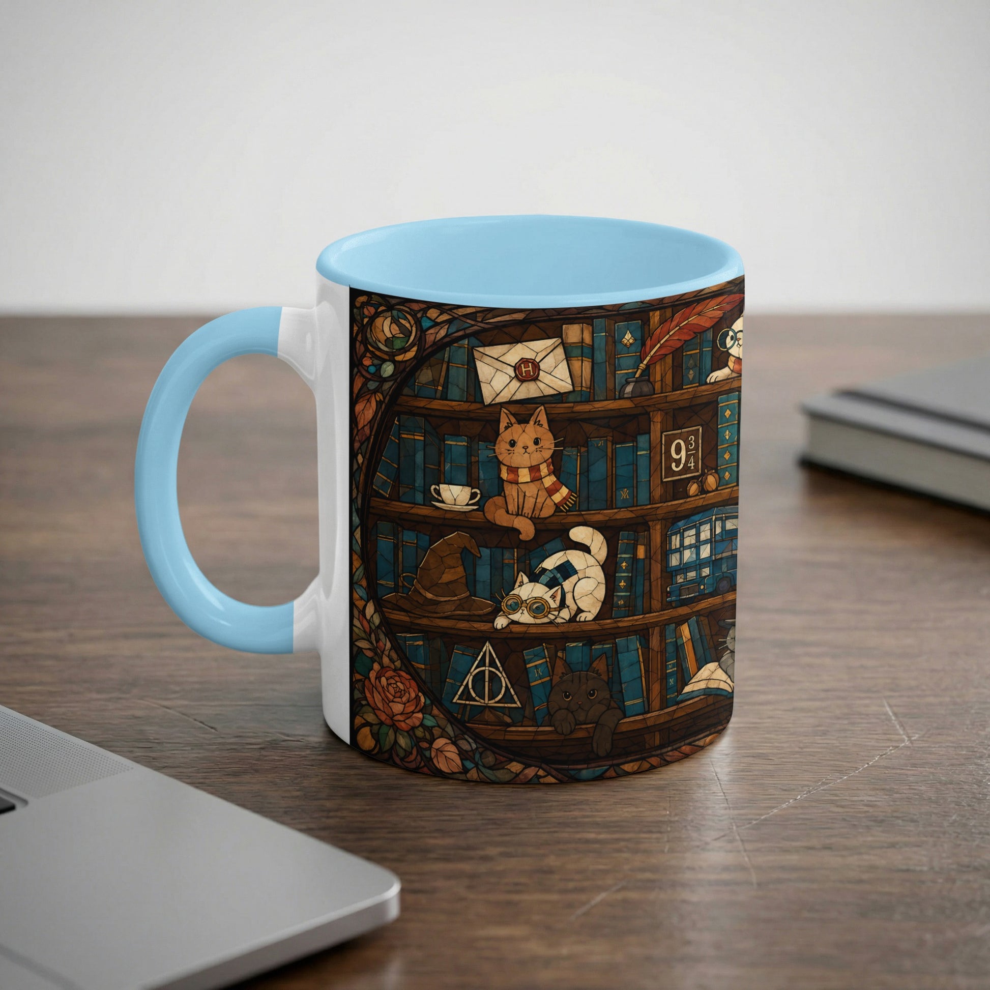 White mug with blue handle featuring a stained-glass design of cats on bookshelves.