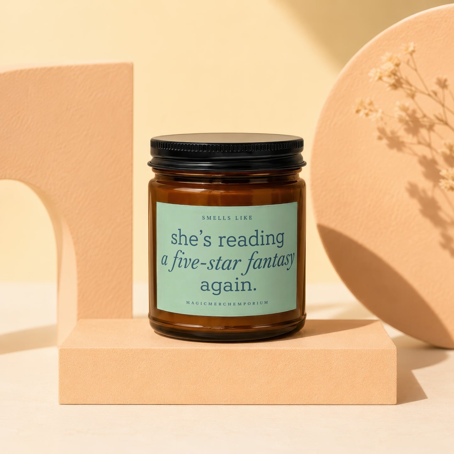 Candle with black lid and teal label reading "she's reading a five-star fantasy again."