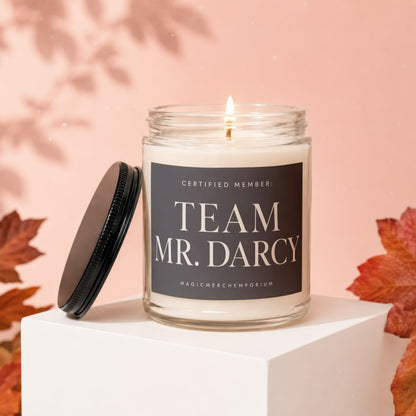 Candle with label "Team Mr. Darcy" on a white pedestal, with autumn leaves.