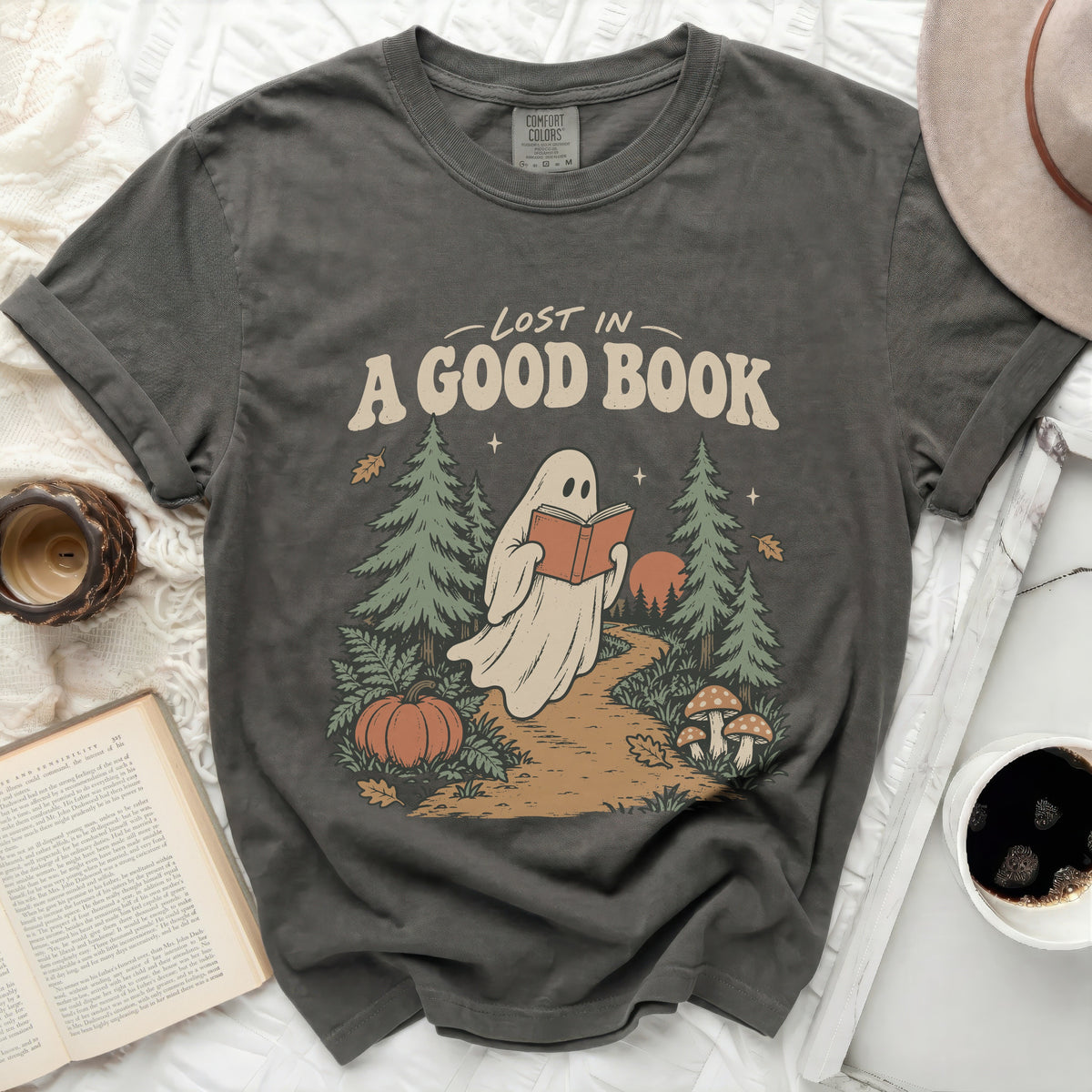Ghost reading "A Good Book" in a forest with a pumpkin.