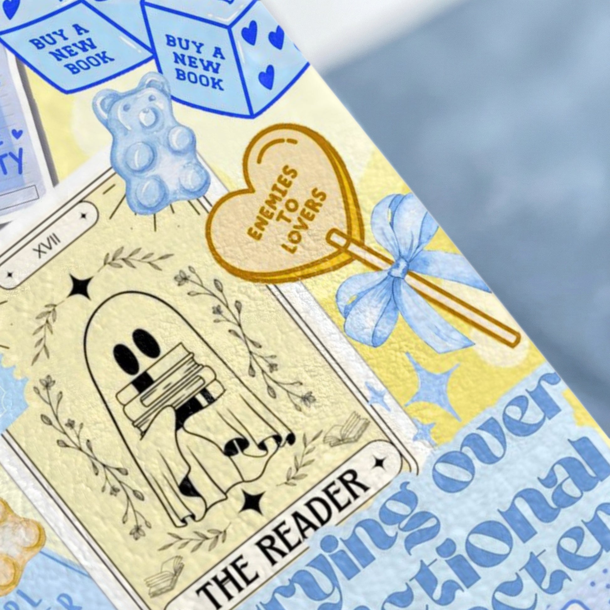 Tarot card with ghost reading books, gummy bear, and "Enemies to Lovers" heart.