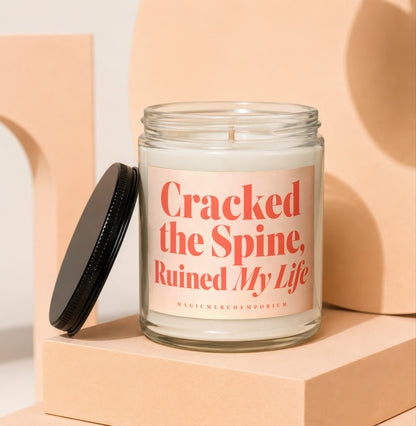 Glass candle with text "Cracked the Spine, Ruined My Life" on the label.
