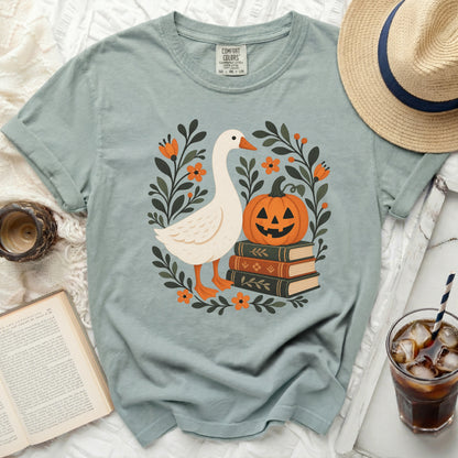 Goose, pumpkin, and books graphic on a light blue t-shirt.