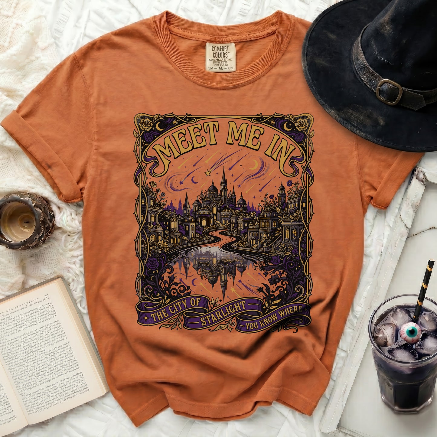 Orange t-shirt with "Meet Me In The City of Starlight You Know Where" graphic.