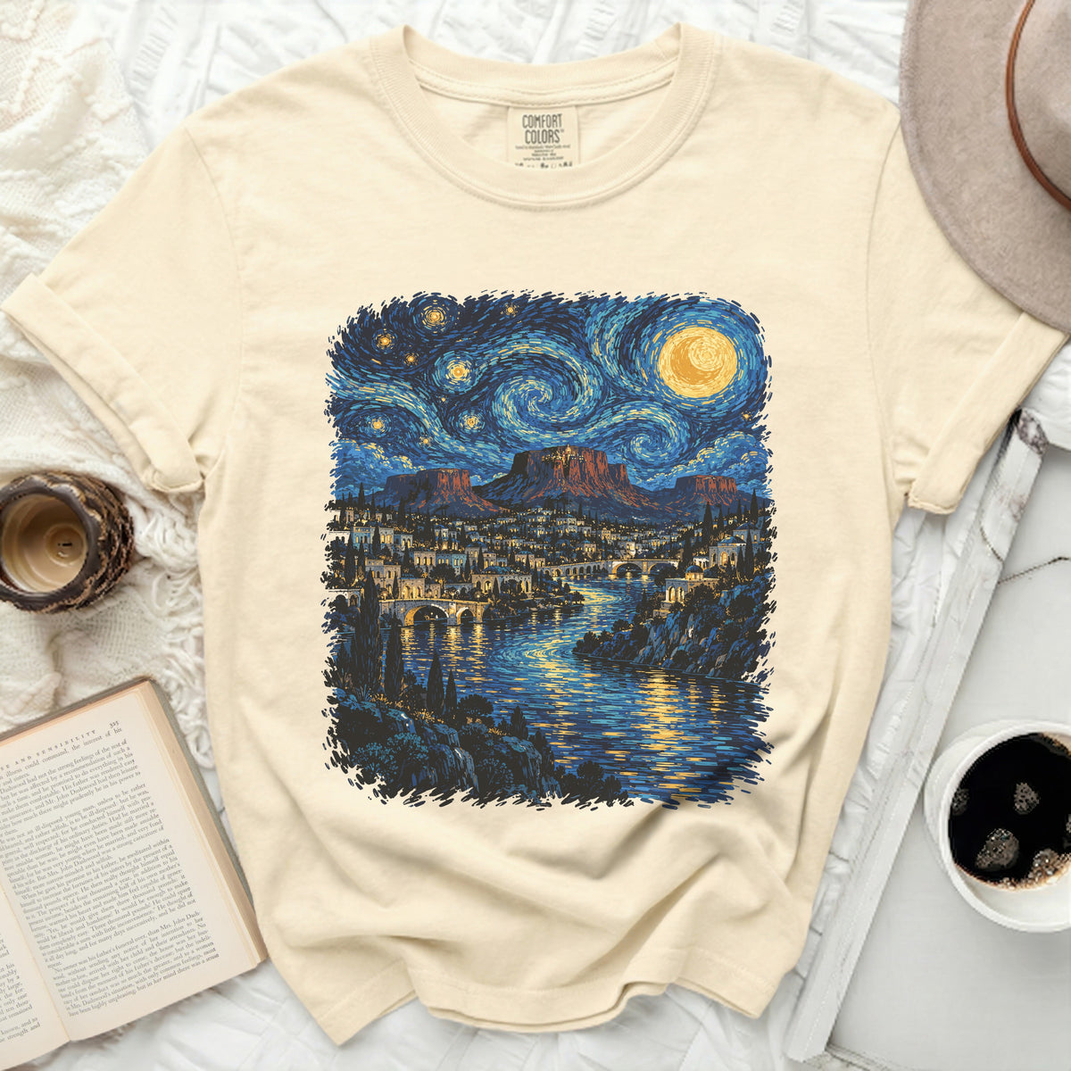 Cream t-shirt with Van Gogh-style starry night print of a city and river.