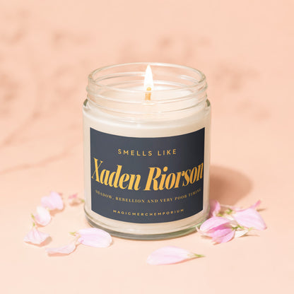 Scented candle labeled "Xaden Riorson" with flower petals on a peach background.