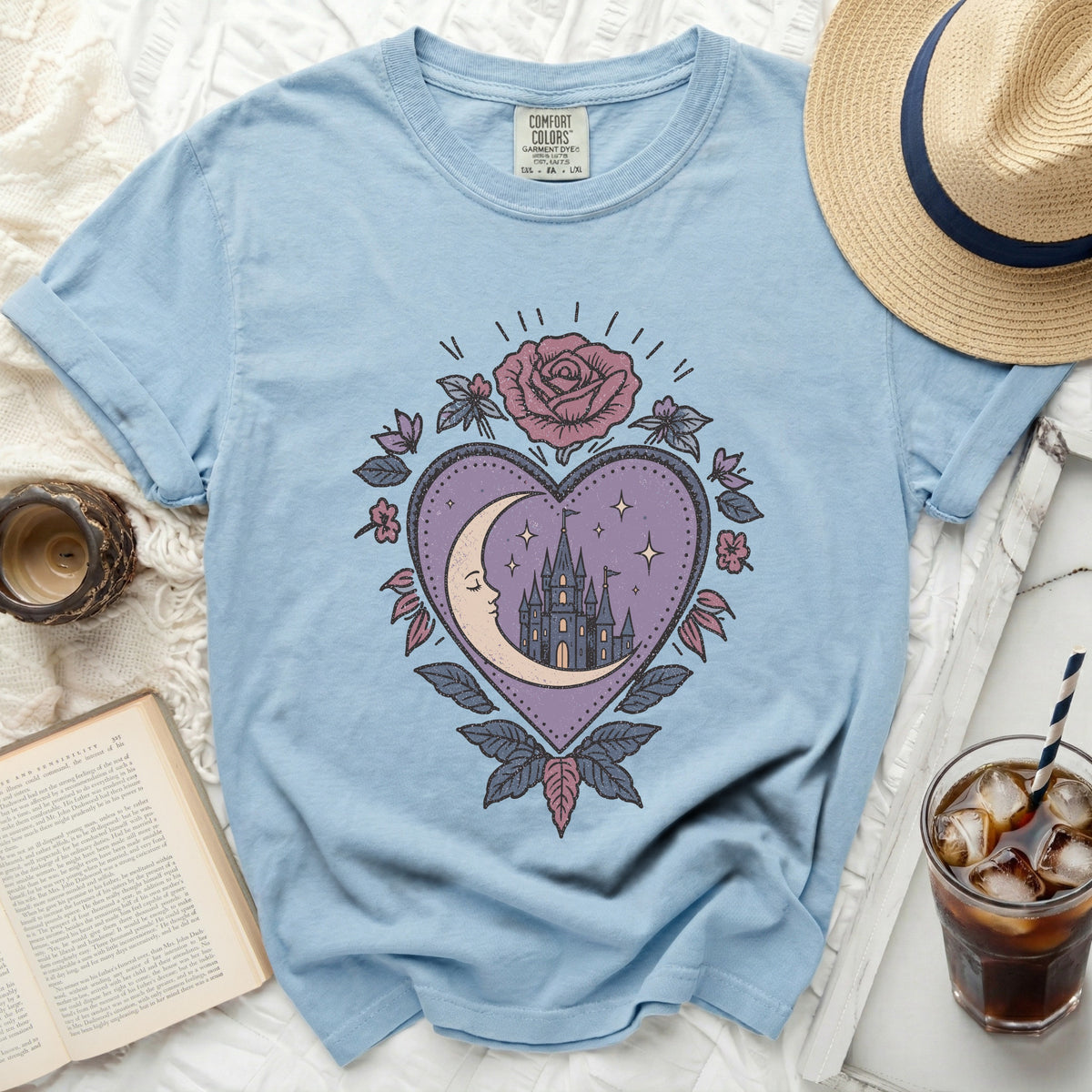 Light blue t-shirt with mystical heart, moon, and castle graphic.