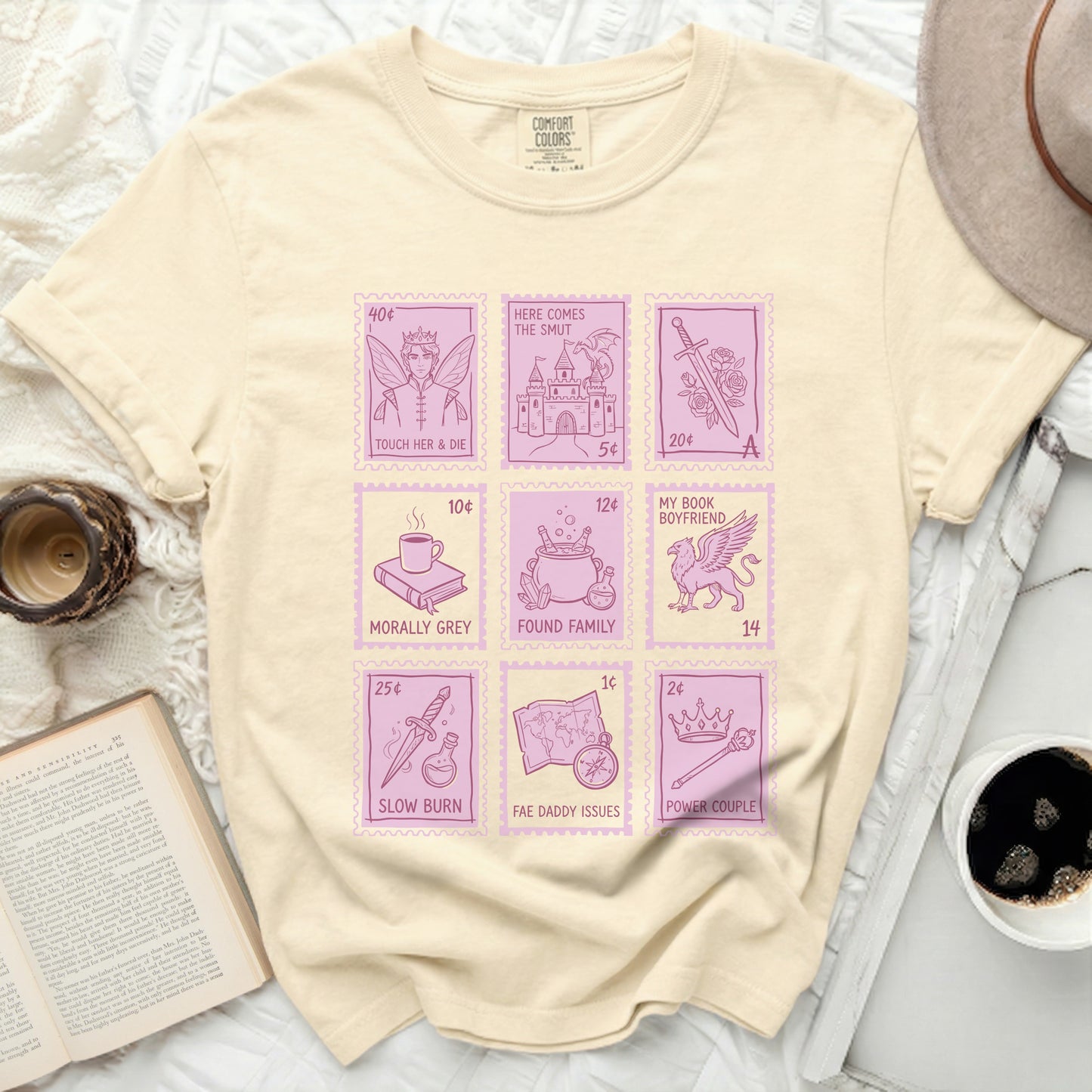 Light yellow t-shirt with pink stamp graphics of book titles.