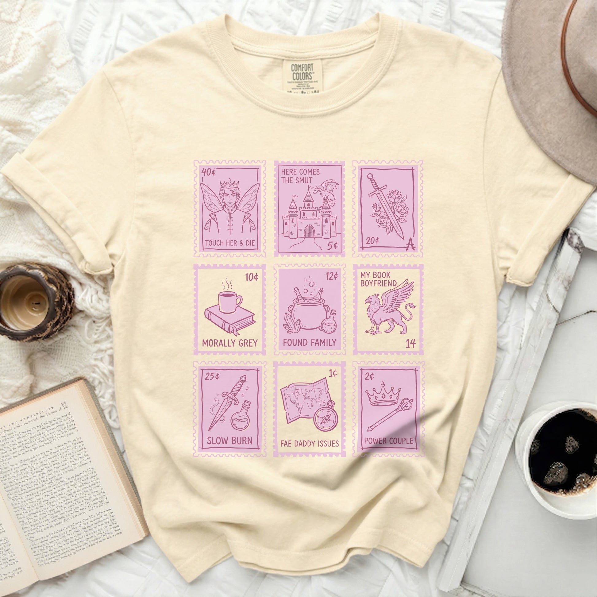 Light yellow t-shirt with pink stamp graphics of book titles.