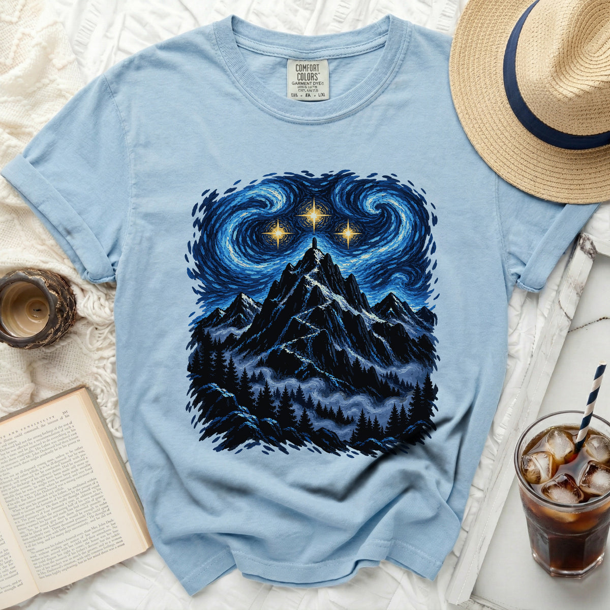 Light blue t-shirt with a mountain landscape under a starry, swirling sky.