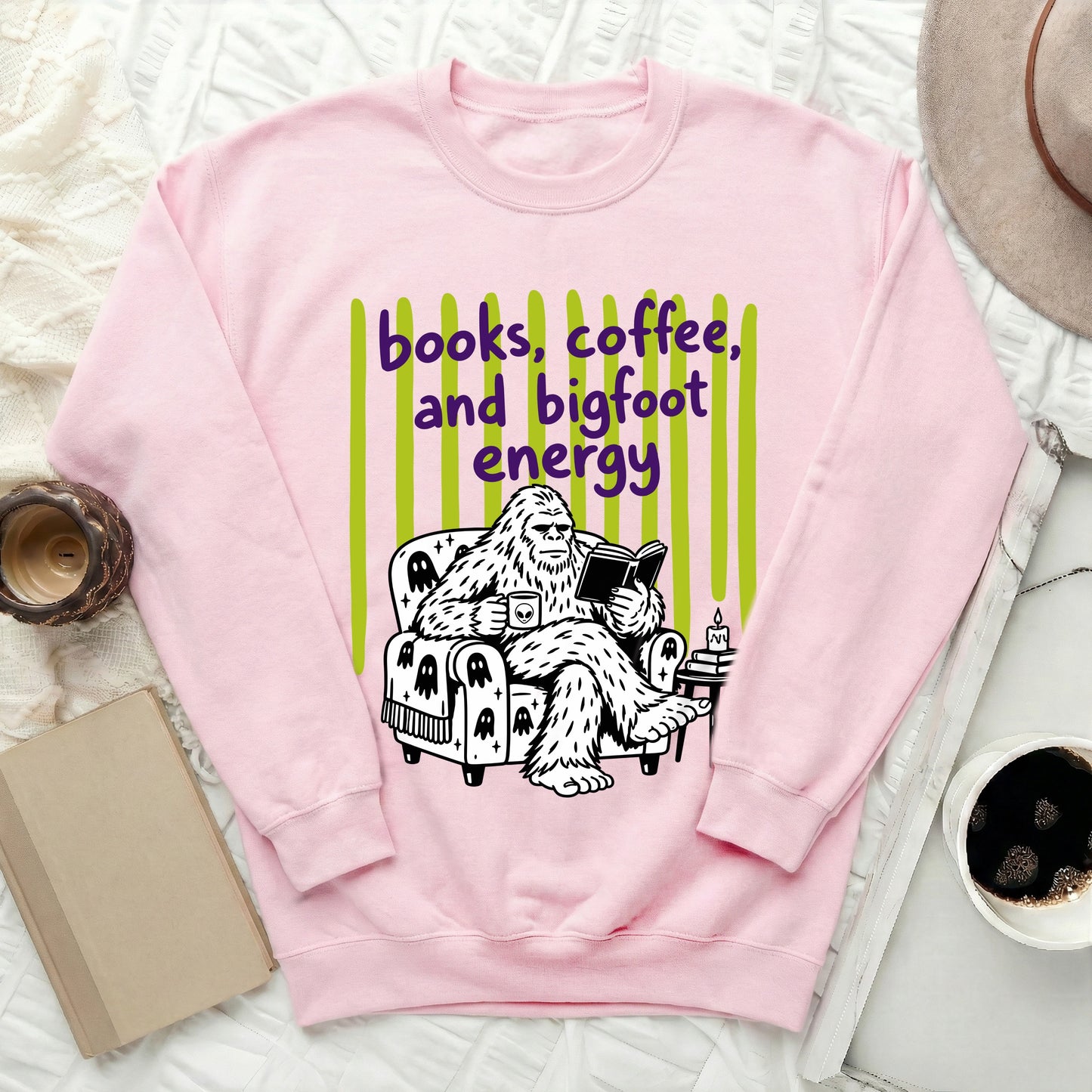 Pink sweatshirt with Bigfoot reading and drinking coffee, saying "books, coffee, and bigfoot energy."