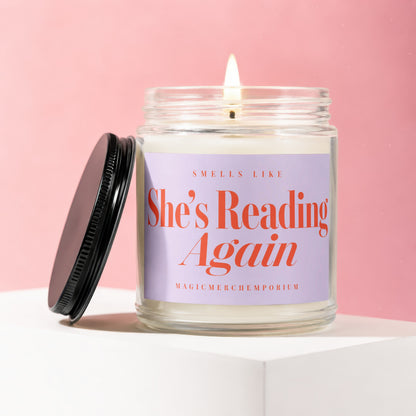 Candle with lit wick, reading "Smells Like She's Reading Again".
