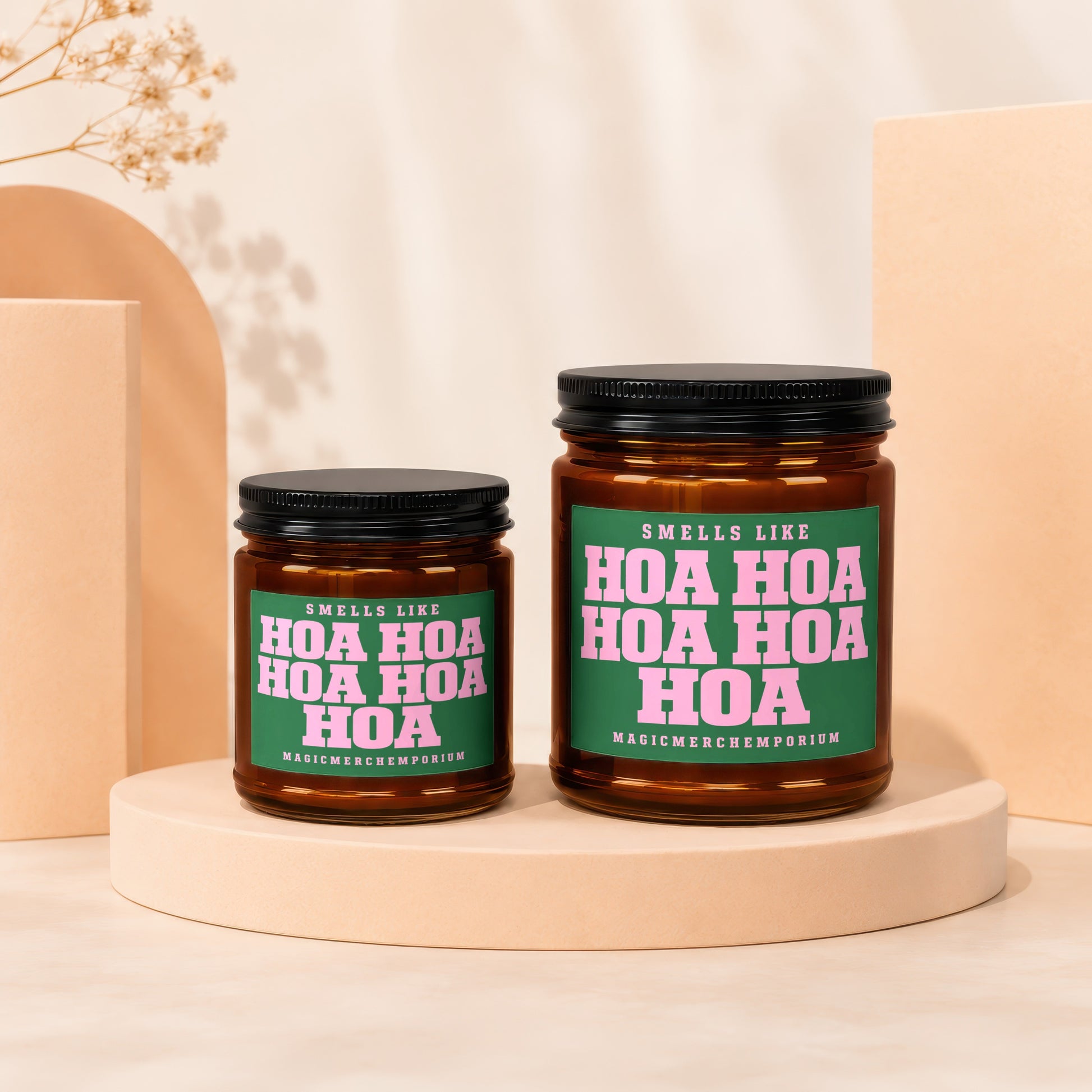 Two amber glass candles with black lids, labeled "Smells Like Hoa Hoa Hoa".