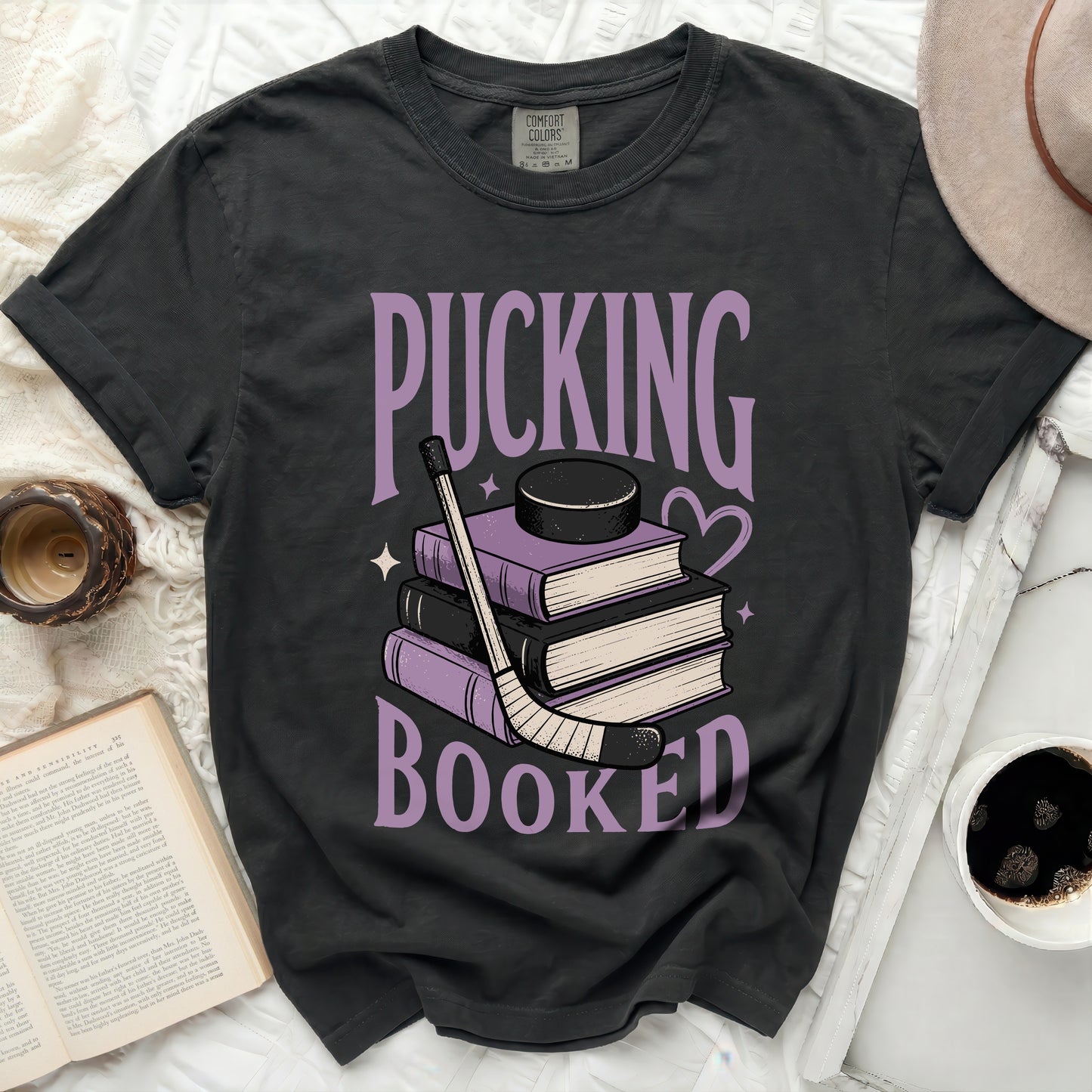 Dark t-shirt with "Pucking Booked" text over stack of books and hockey puck.