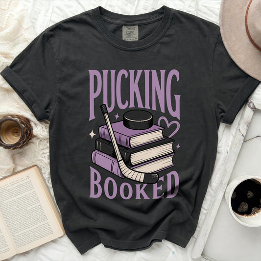Dark t-shirt with "Pucking Booked" text over stack of books and hockey puck.