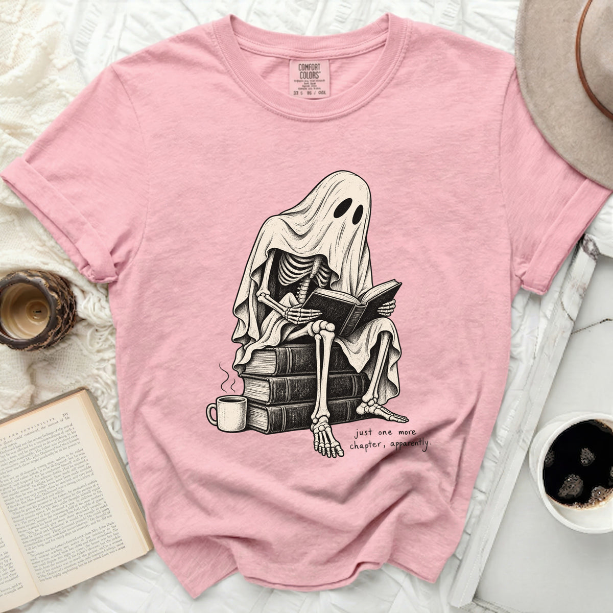 Skeleton ghost reading a book on a stack of books, "just one more chapter, apparently."