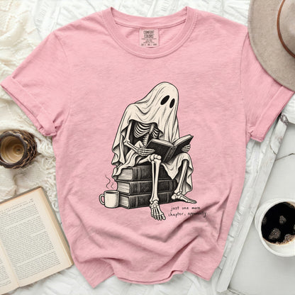 Skeleton ghost reading a book on a stack of books, "just one more chapter, apparently."