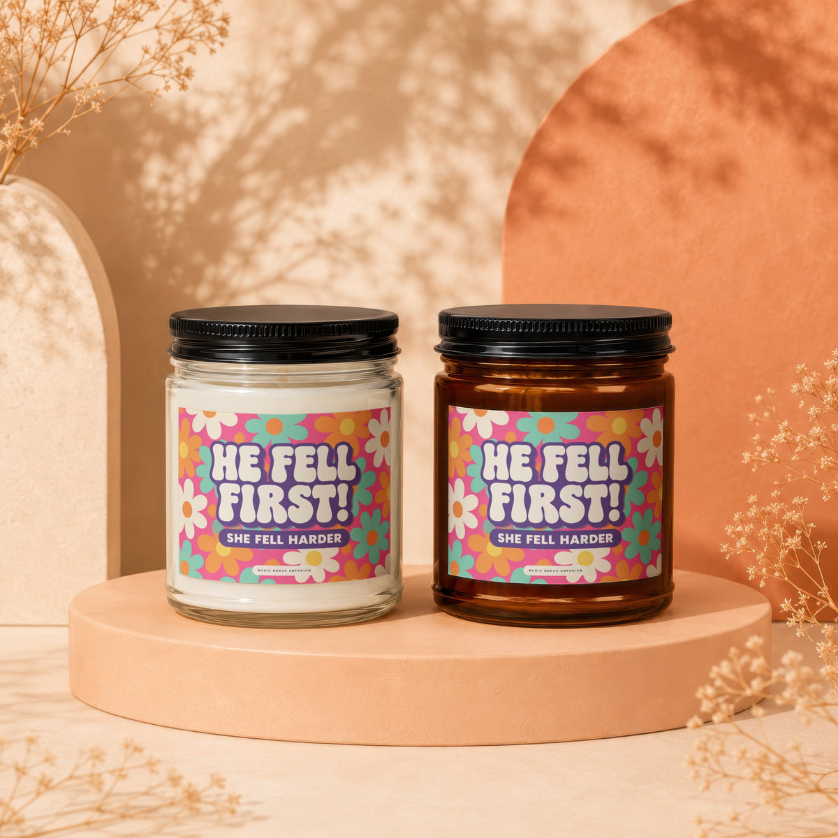 Two candles with "HE FELL FIRST! SHE FELL HARDER" text on floral labels.