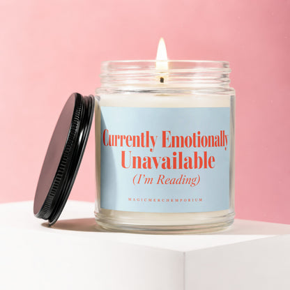 Glass candle with burning wick, light blue label reading "Currently Emotionally Unavailable (I'm Reading)".