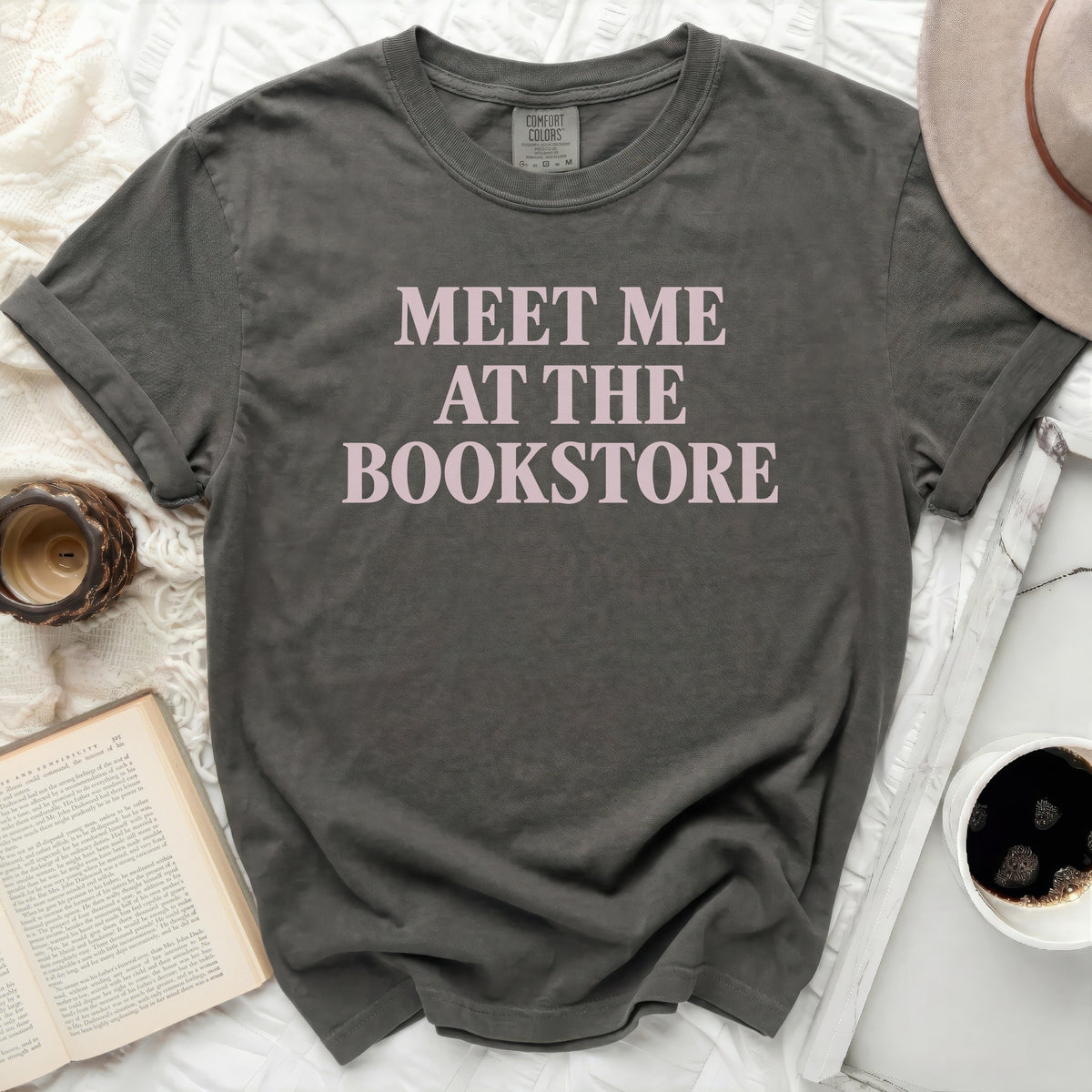 Dark grey t-shirt with "MEET ME AT THE BOOKSTORE" printed in pink.