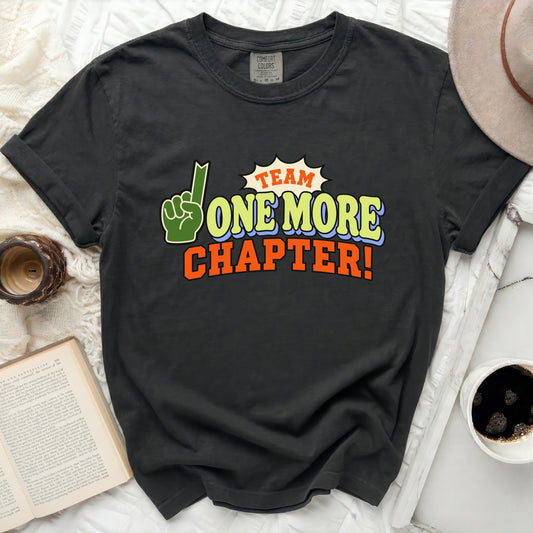 Black t-shirt with "Team One More Chapter!" graphic and a green finger pointing up.