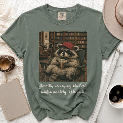 T-shirt graphic of a raccoon wearing a red hat and sunglasses drinking from a cup.