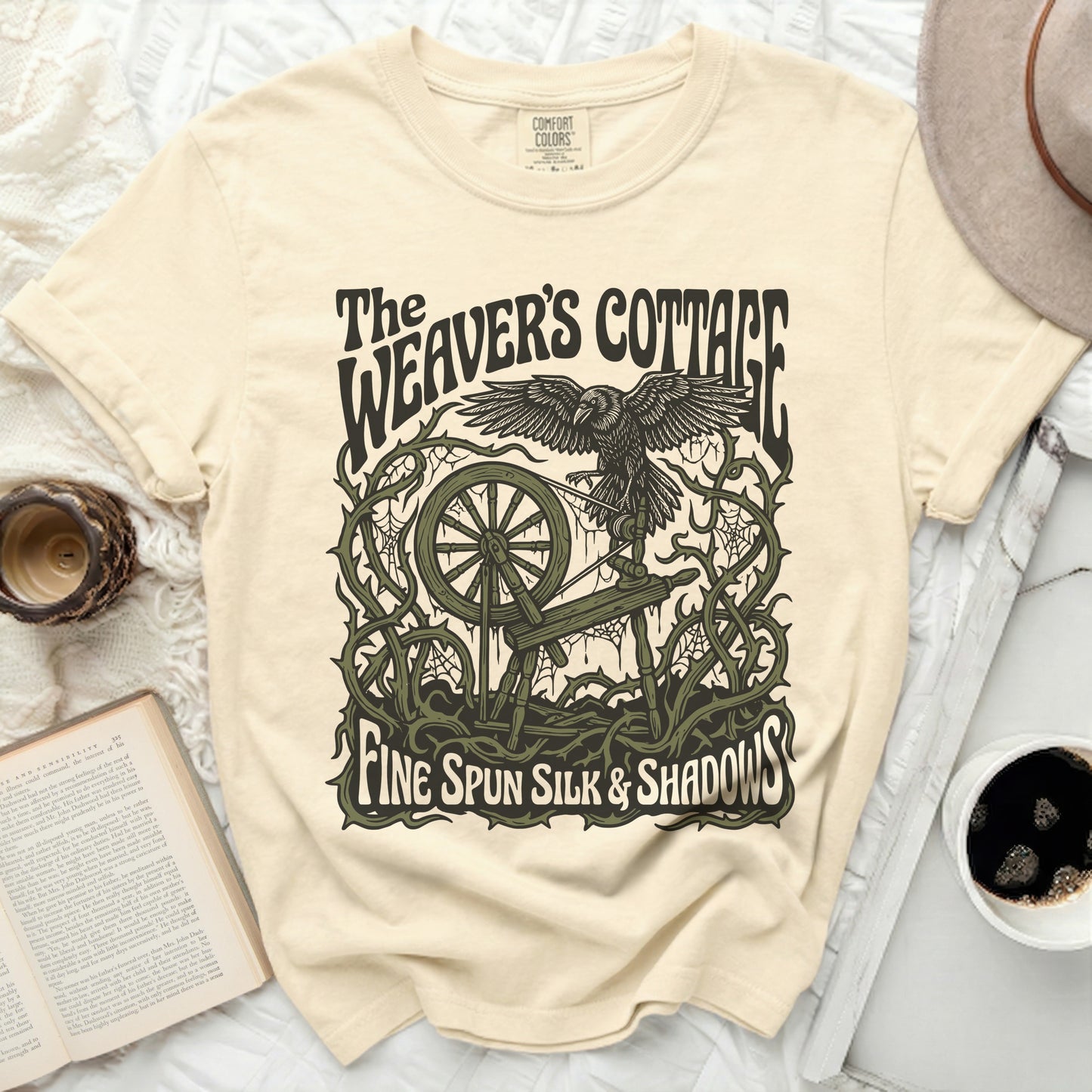 The Weaver's Cottage shirt with a raven, spinning wheel, and thorns.