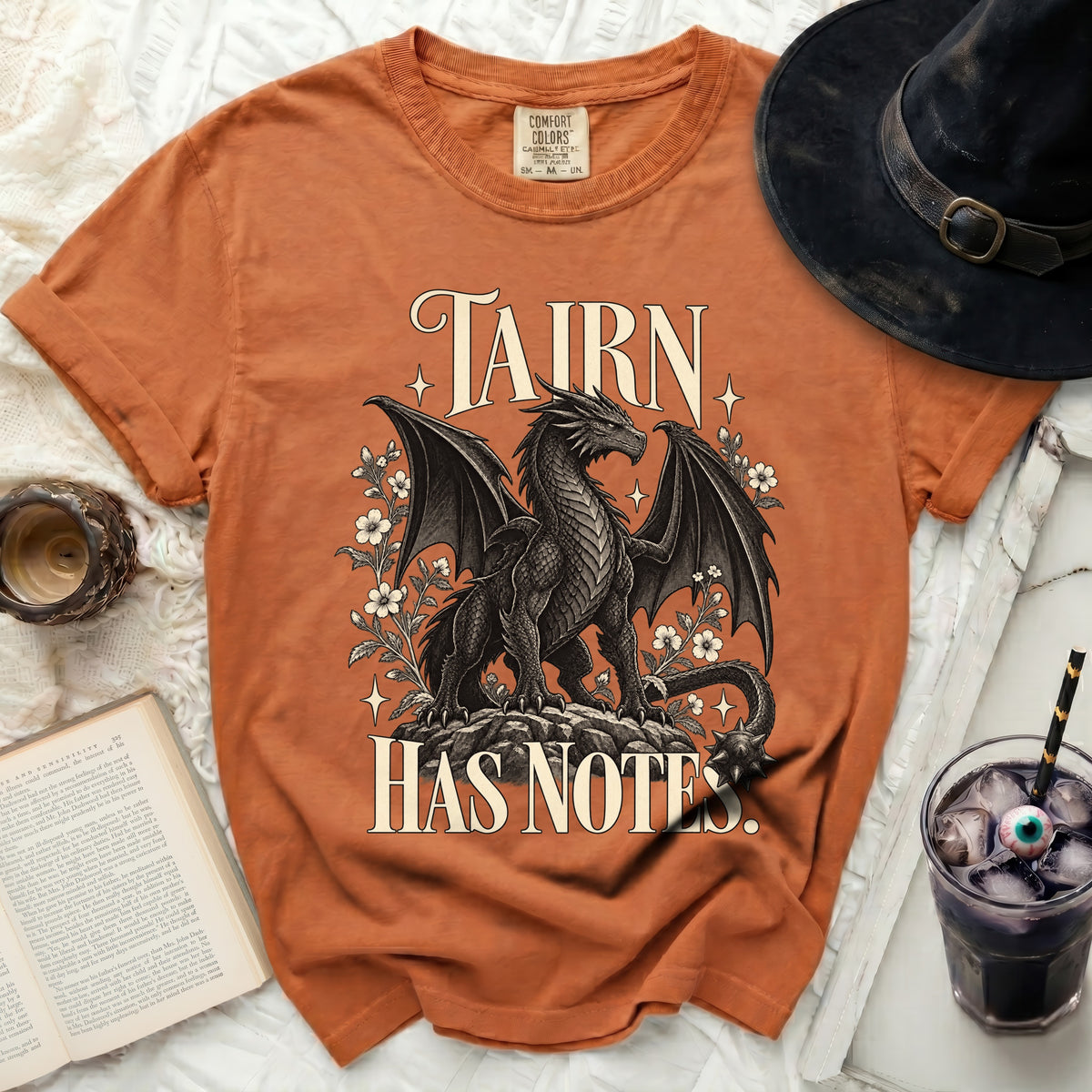 Orange t-shirt with a black dragon graphic and text "TAIRN HAS NOTES".
