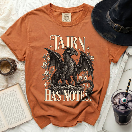 Orange t-shirt with a black dragon graphic and text "TAIRN HAS NOTES".