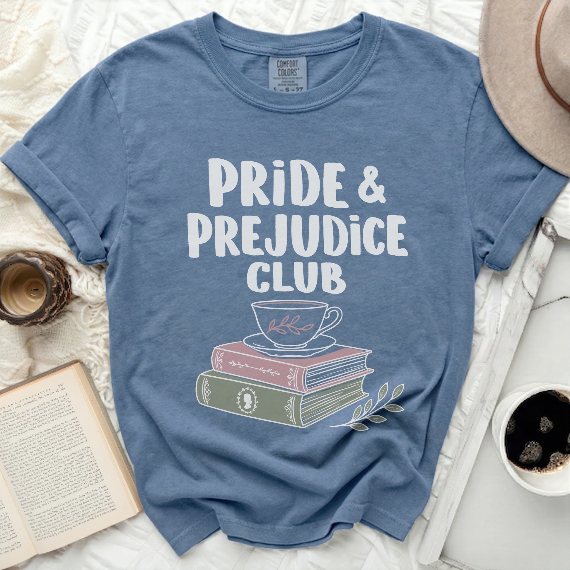 Blue t-shirt with "Pride & Prejudice Club" text above a cup and books.