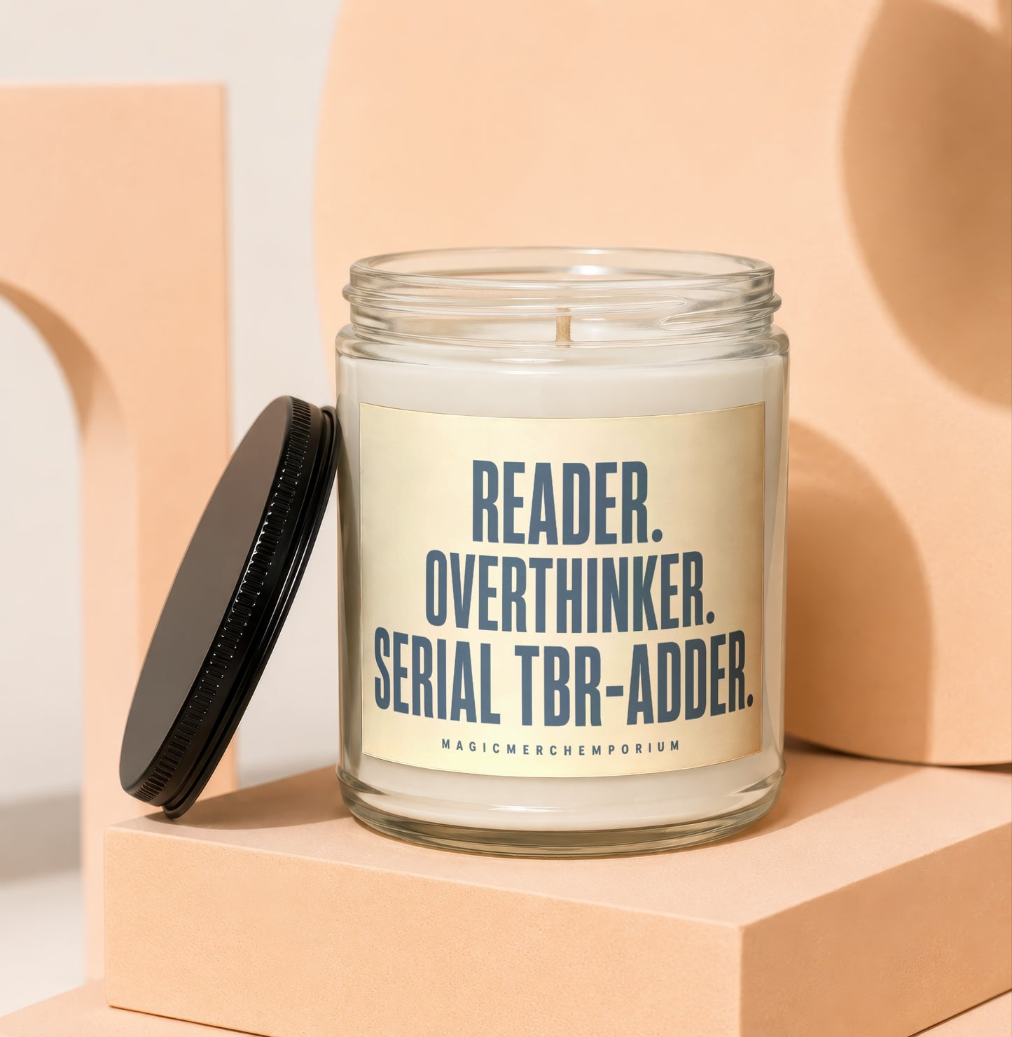 Glass candle with a cream label reading "READER. OVERTHINKER. SERIAL TBR-ADDER."