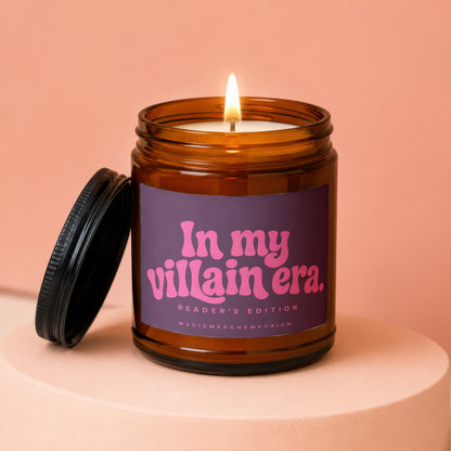 Amber jar candle with lit wick and black lid, labeled "In my villain era."