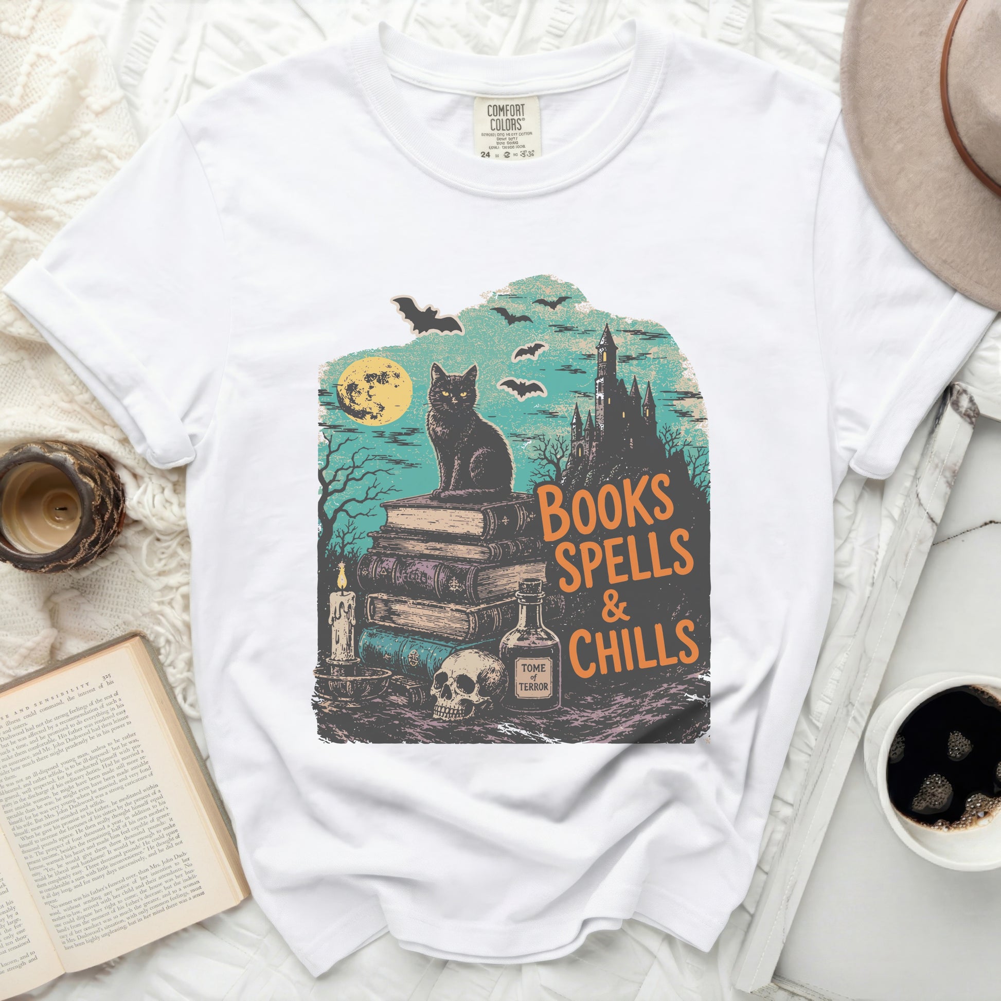 White t-shirt with "Books Spells & Chills" Halloween graphic.