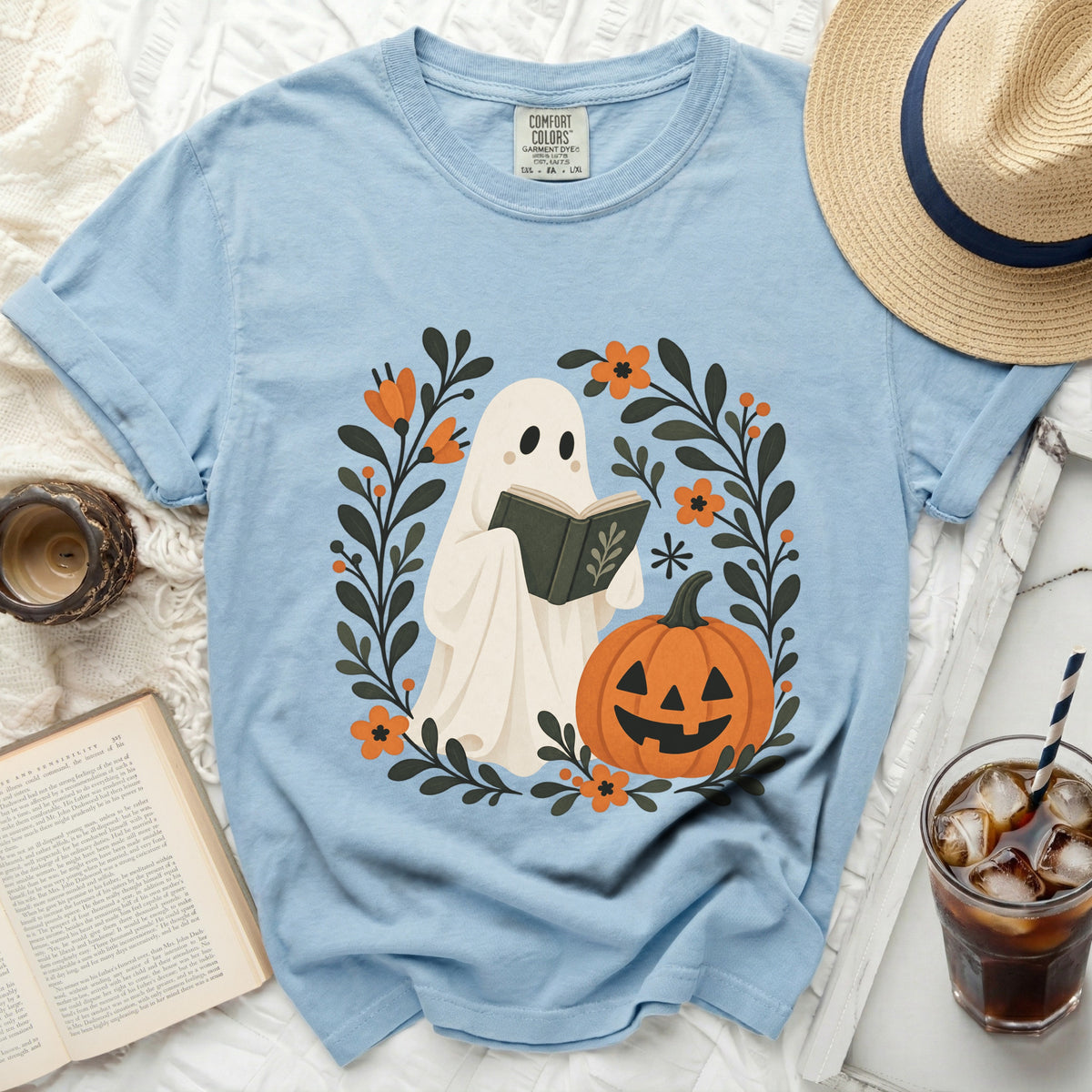 Light blue Comfort Colors t-shirt with ghost reading a book and pumpkin graphic.