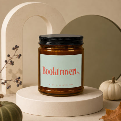 Amber jar candle with "Booktrovert (n.)" and "MAGIC MERCH EMPORIUM" text on label.
