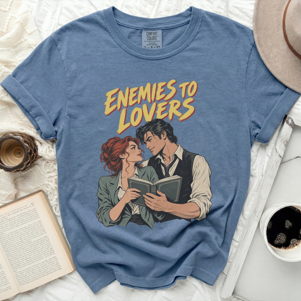 Blue t-shirt with "ENEMIES TO LOVERS" text and comic illustration of a couple.