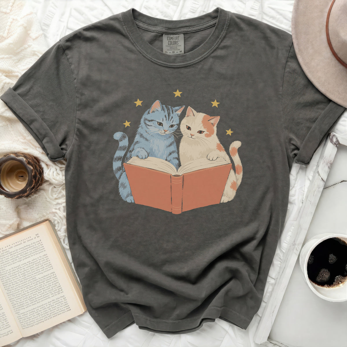 Two cats reading a book with stars above, on a dark gray t-shirt.