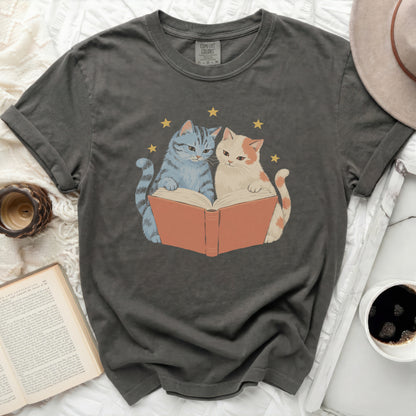 Two cats reading a book with stars above, on a dark gray t-shirt.