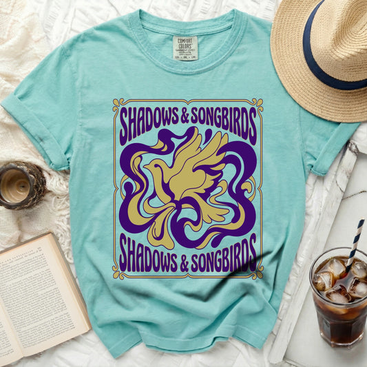 Aqua t-shirt with "Shadows & Songbirds" text and a yellow and purple bird design.