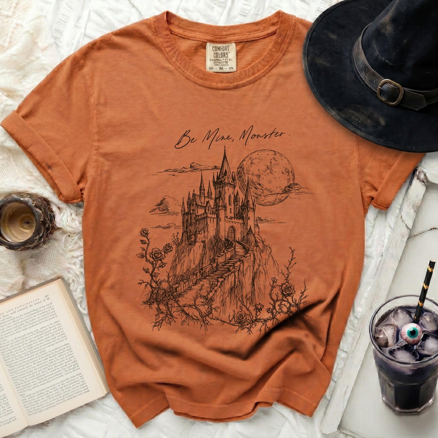 Orange Comfort Colors t-shirt with castle, moon, and "Be Mine, Monster" text.