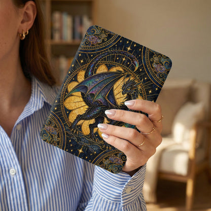 A person in a blue-and-white striped shirt holds an e-reader with an intricate dark blue and gold dragon design.