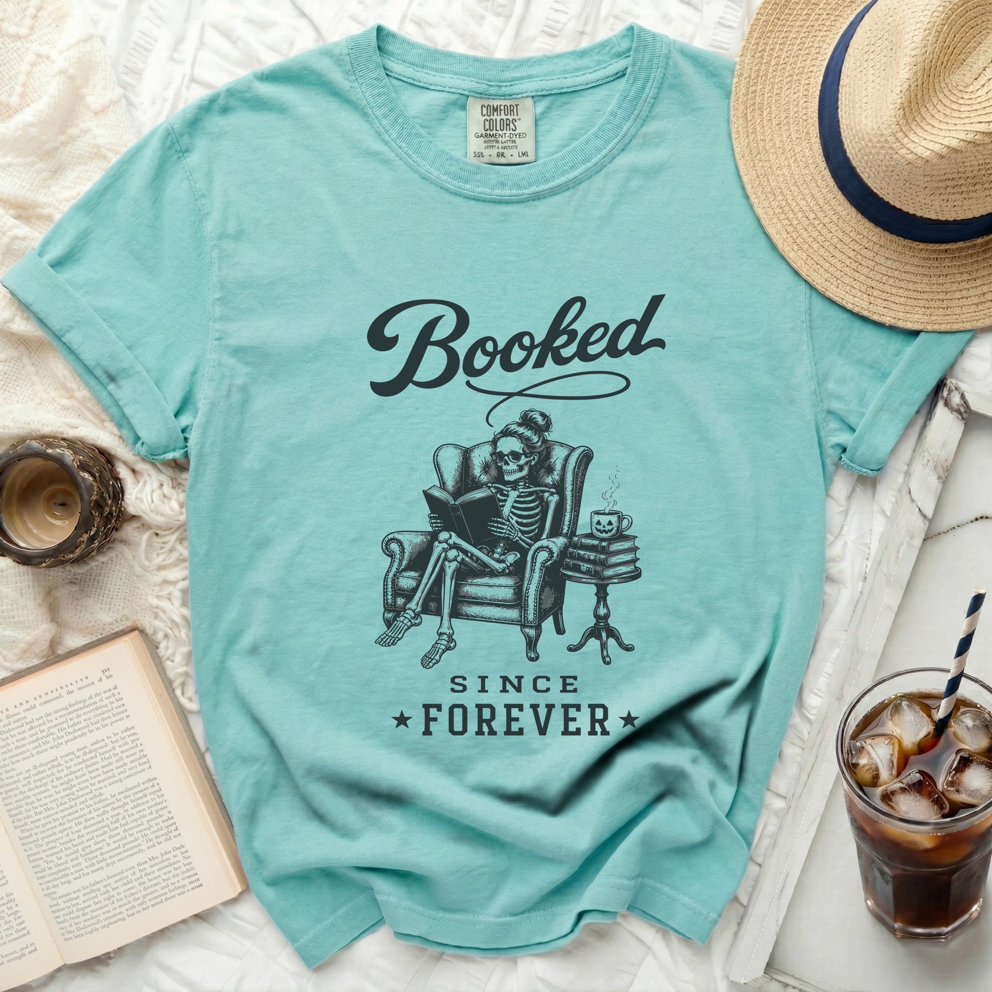 Aqua t-shirt with skeleton reading book graphic and "Booked Since Forever" text.