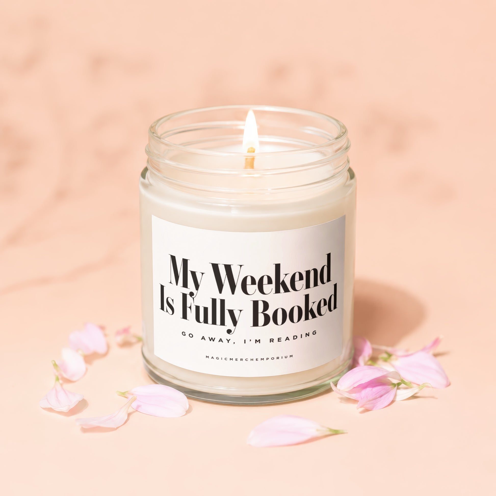 Candle with "My Weekend Is Fully Booked" text surrounded by pink petals.