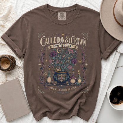 Brown t-shirt with "Cauldron & Crown Apothecary" and magic design.