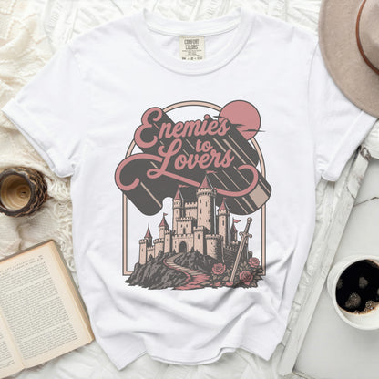 White t-shirt with "Enemies to Lovers" graphic featuring a castle, sword, and roses.