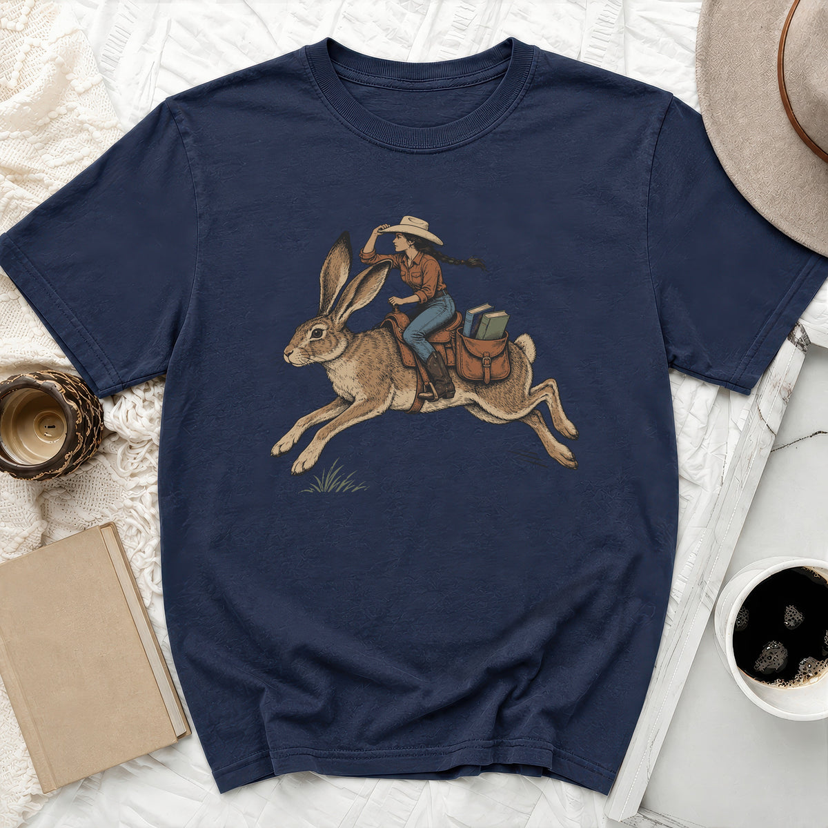 Navy t-shirt with illustration of woman in cowboy hat riding a rabbit carrying books.